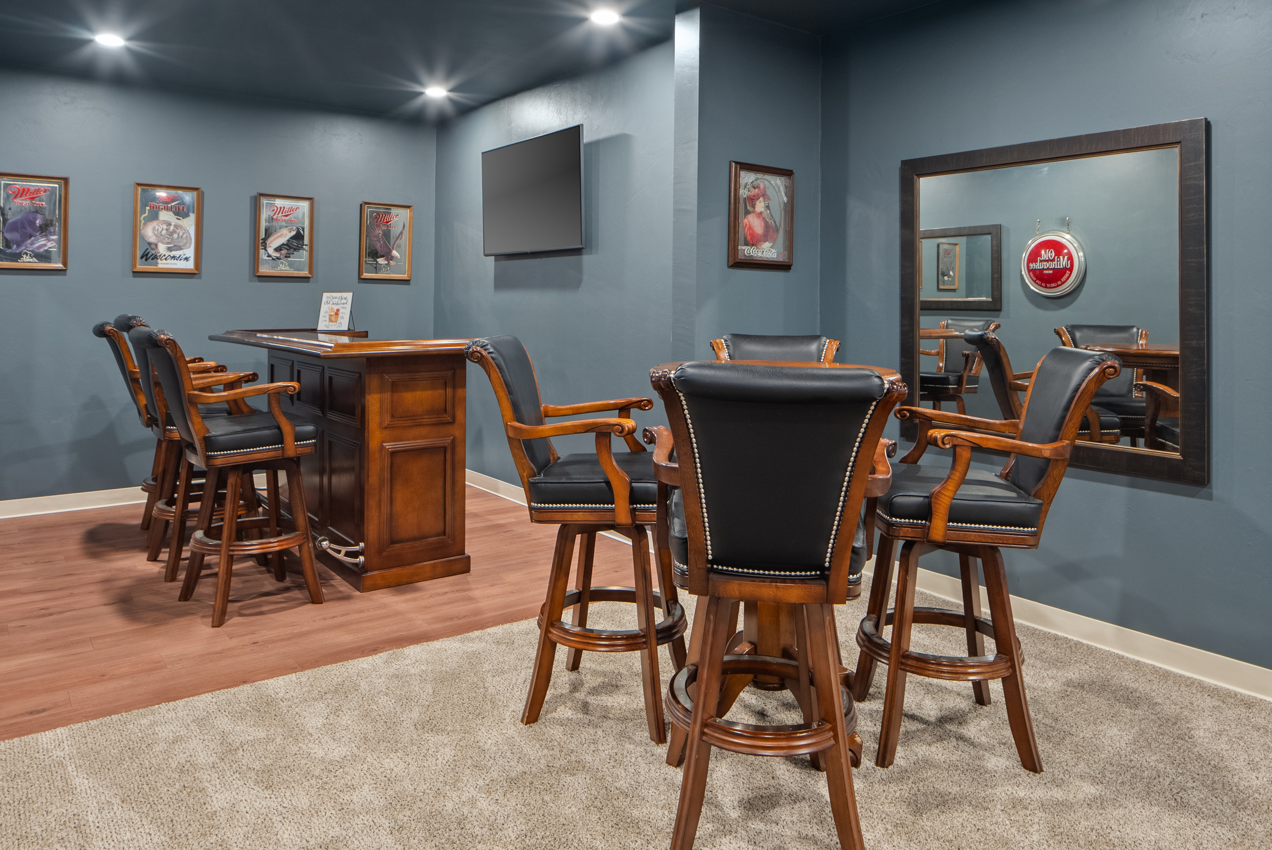Home bar lounge with leather stools and Wisconsin memorabilia at Evergreen Manor